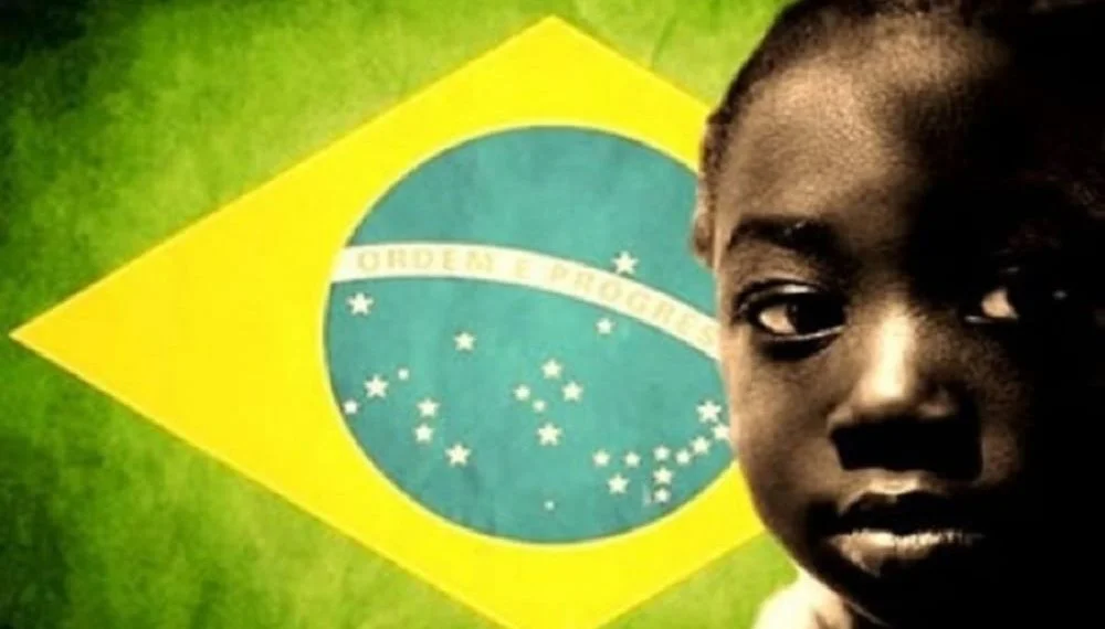 Menino negro em frente à bandeira do Brasil