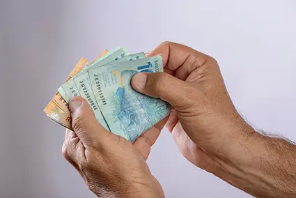 Mão segurando notas de real.