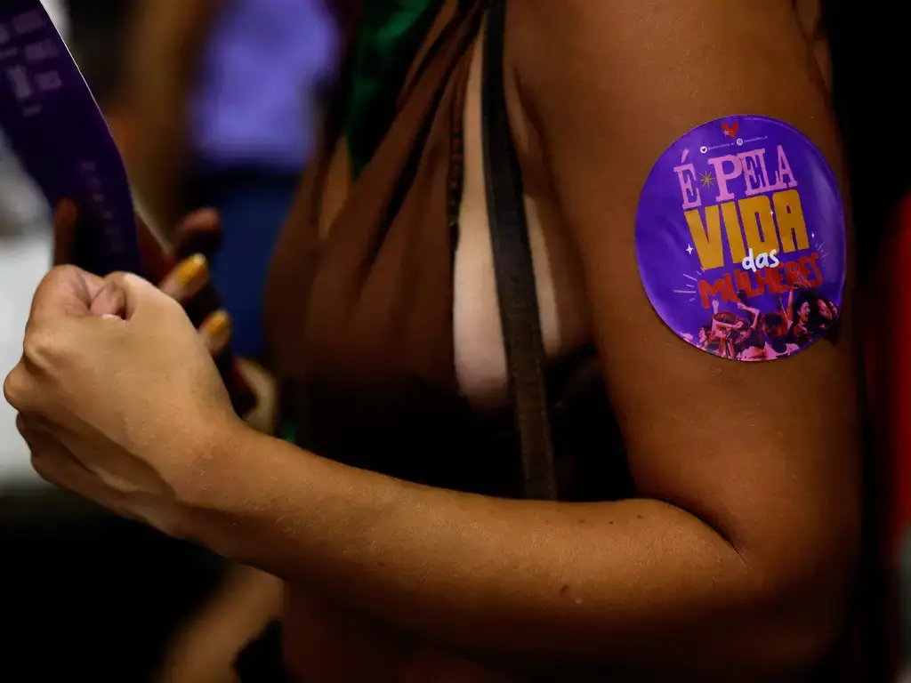 mulher em protesto com adesivo "é pela vida das mulheres"