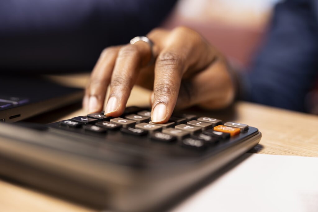 mão de uma mulher negra apertando botão de uma calculadora