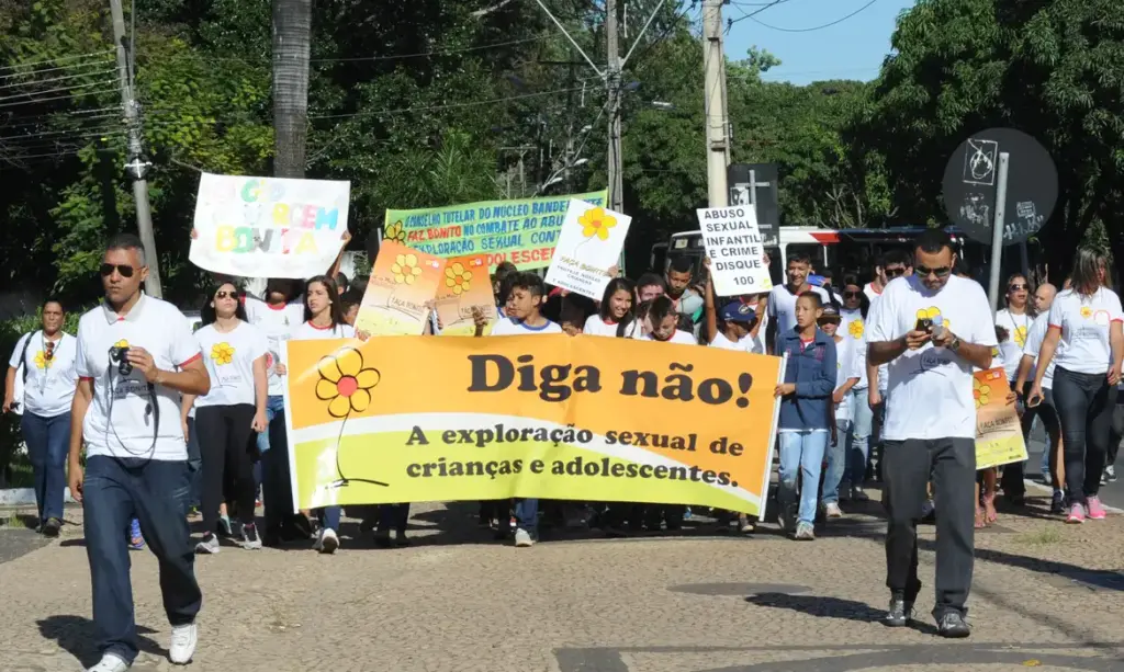 Imagem de crianças e adolescentes em uma manifestação de rua, com cartazes pedindo o fim do abuso e exploração sexual.