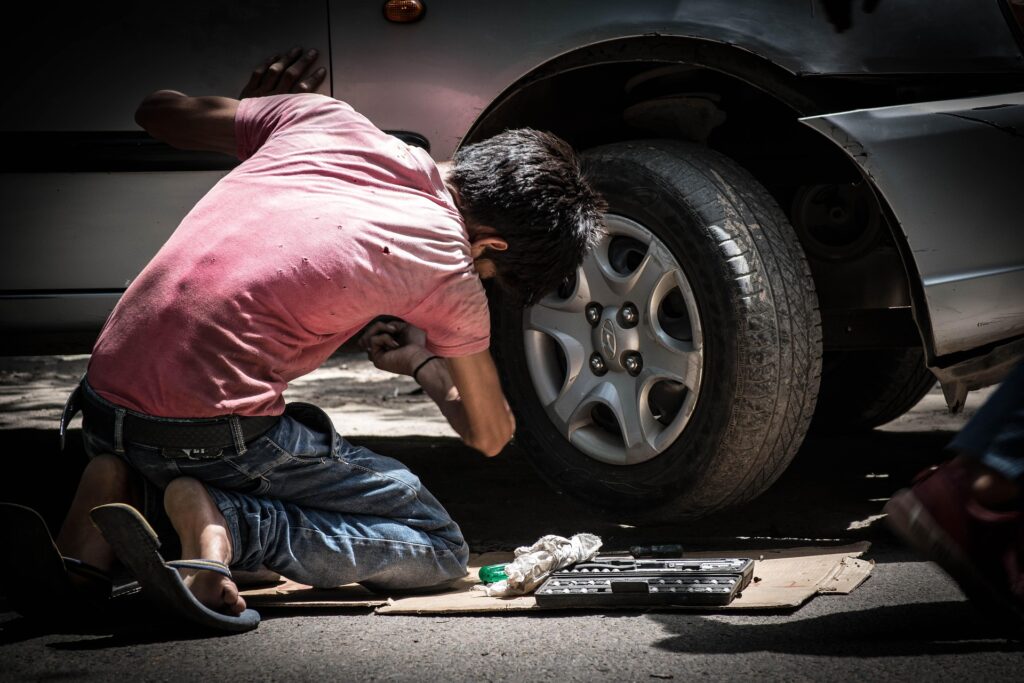 Garoto trabalhando no conserto de um carro como ilustração para trabalho infantil