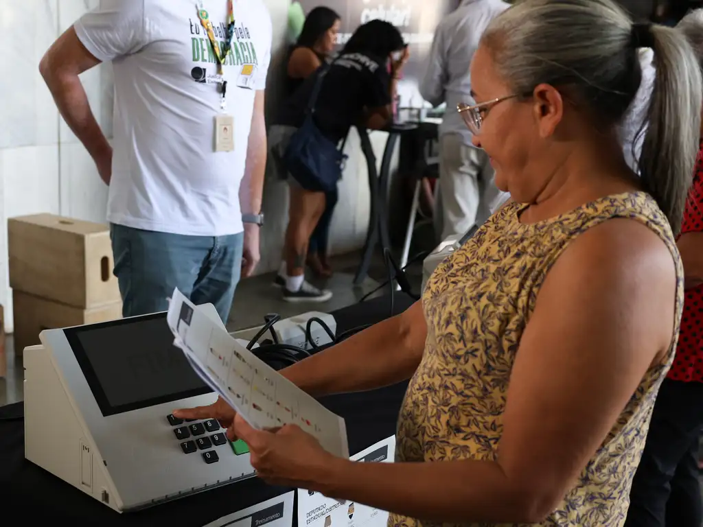 Mulher apertando botões da urna eletrônica